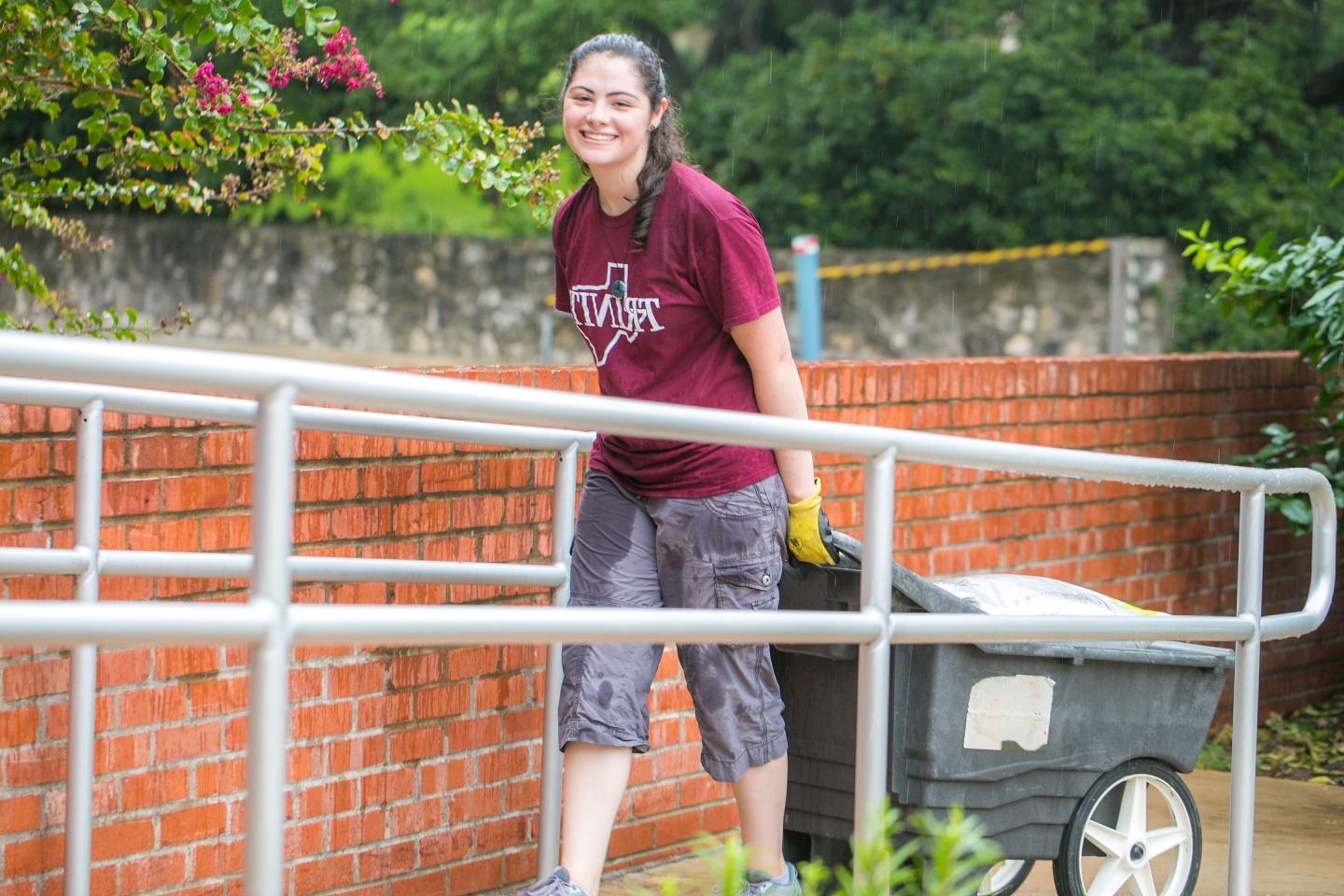 Student carrying a wheel barrow to pick up recycling