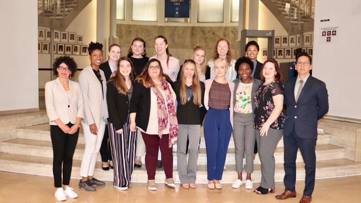 Student group poses in front of banner for The Hague.