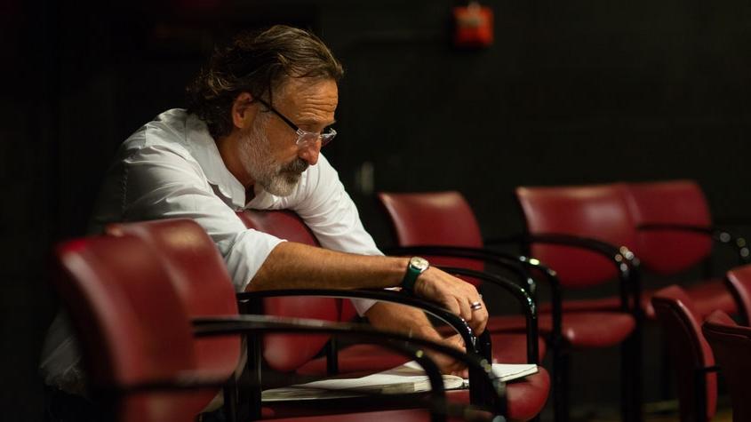 Robert Prestigiacomo, seated, makes notes on a red chair. 