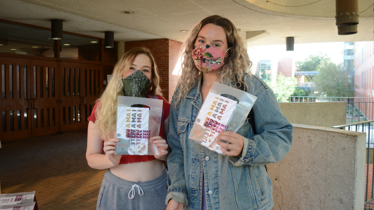 two students with voting swag outside of coates library